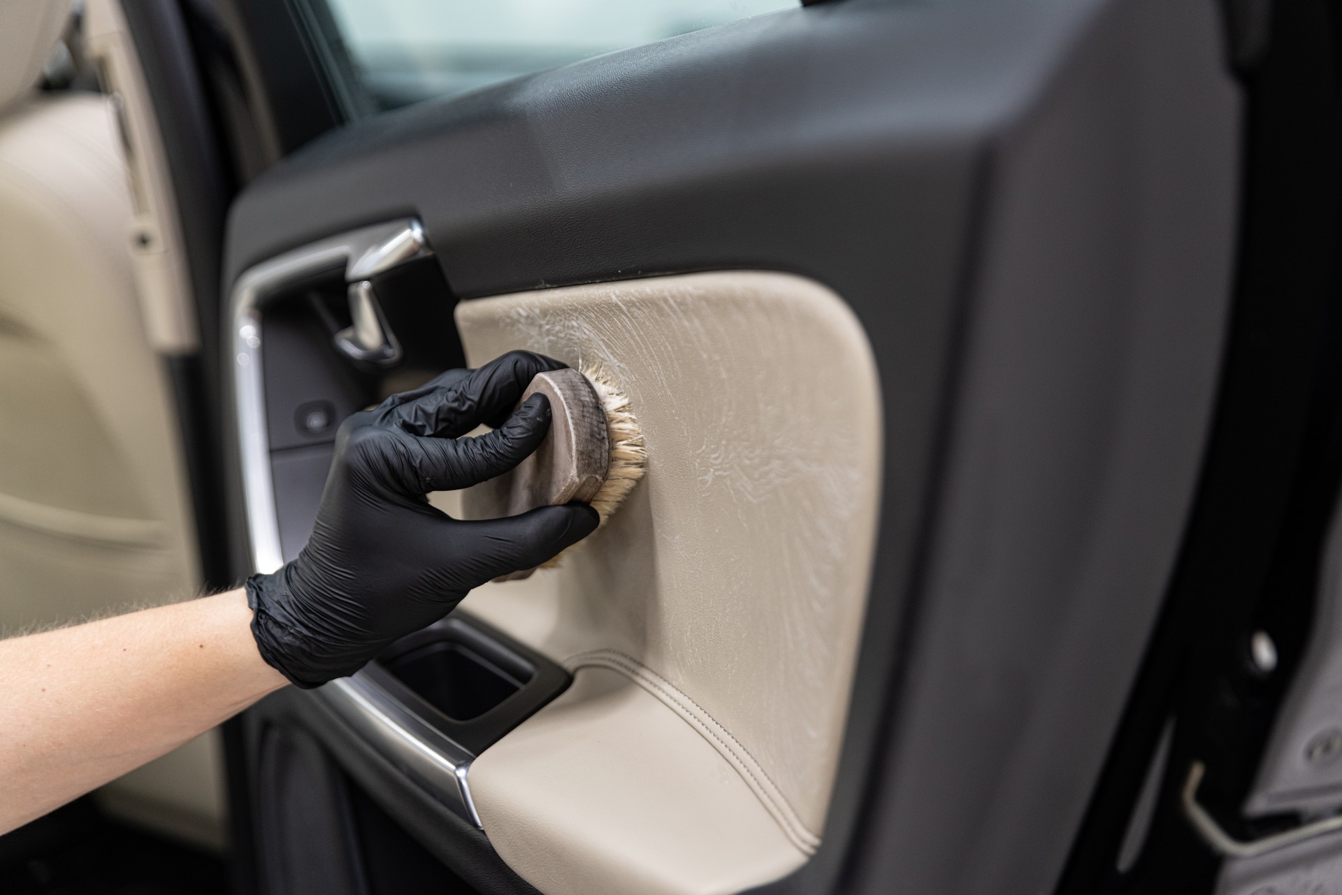 Man cleaning car leather interior with brush.